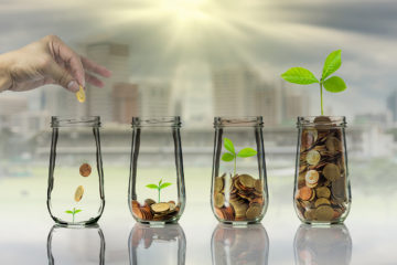 Hand putting Gold coins and seed in clear bottle on cityscape ph