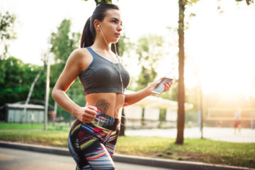 Athletic girl jogging with headphones in park